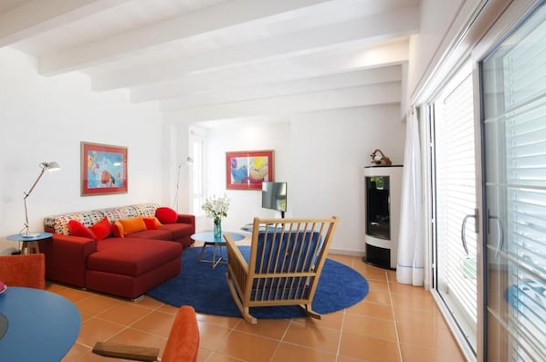 A living room with a red sofa, a blue rug, a wooden chair, and two paintings on the wall. - Piccolo Grand Hotel (Pizzo)