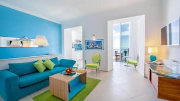 Un soggiorno moderno con un divano blu, un tavolino in legno e un tappeto verde. C'è una zona pranzo con tavolo e sedie, e un balcone con vista.
