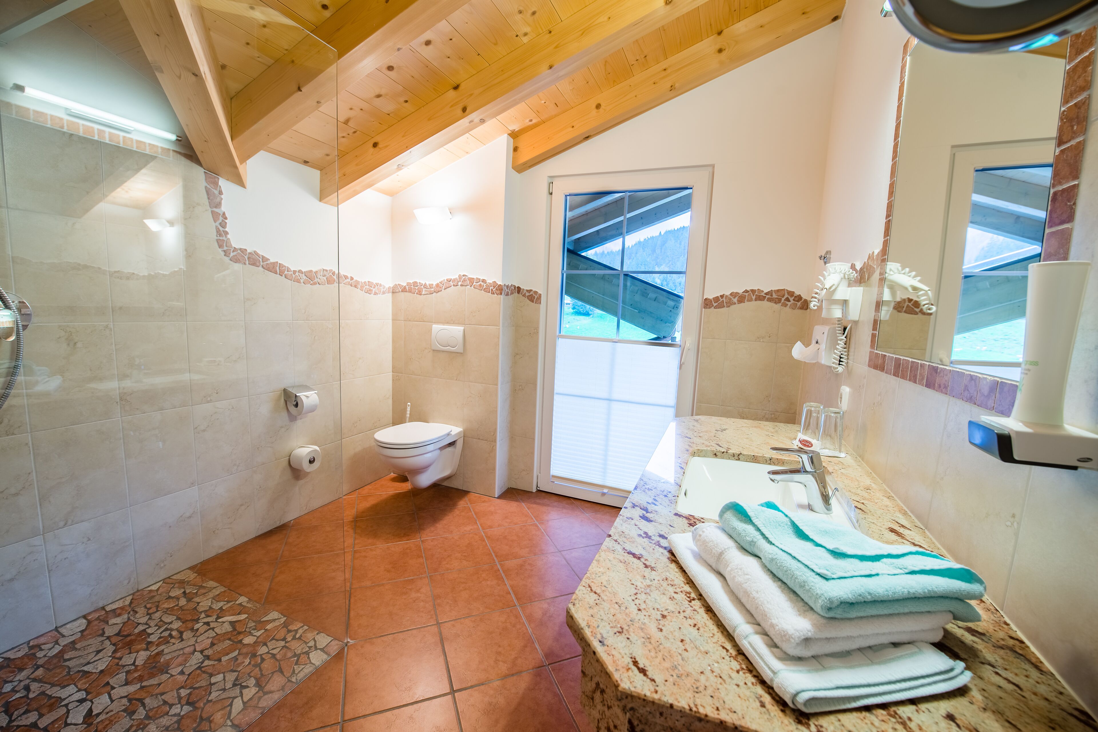 Een badkamer met een douche, toilet en wastafel, voorzien van handdoeken.