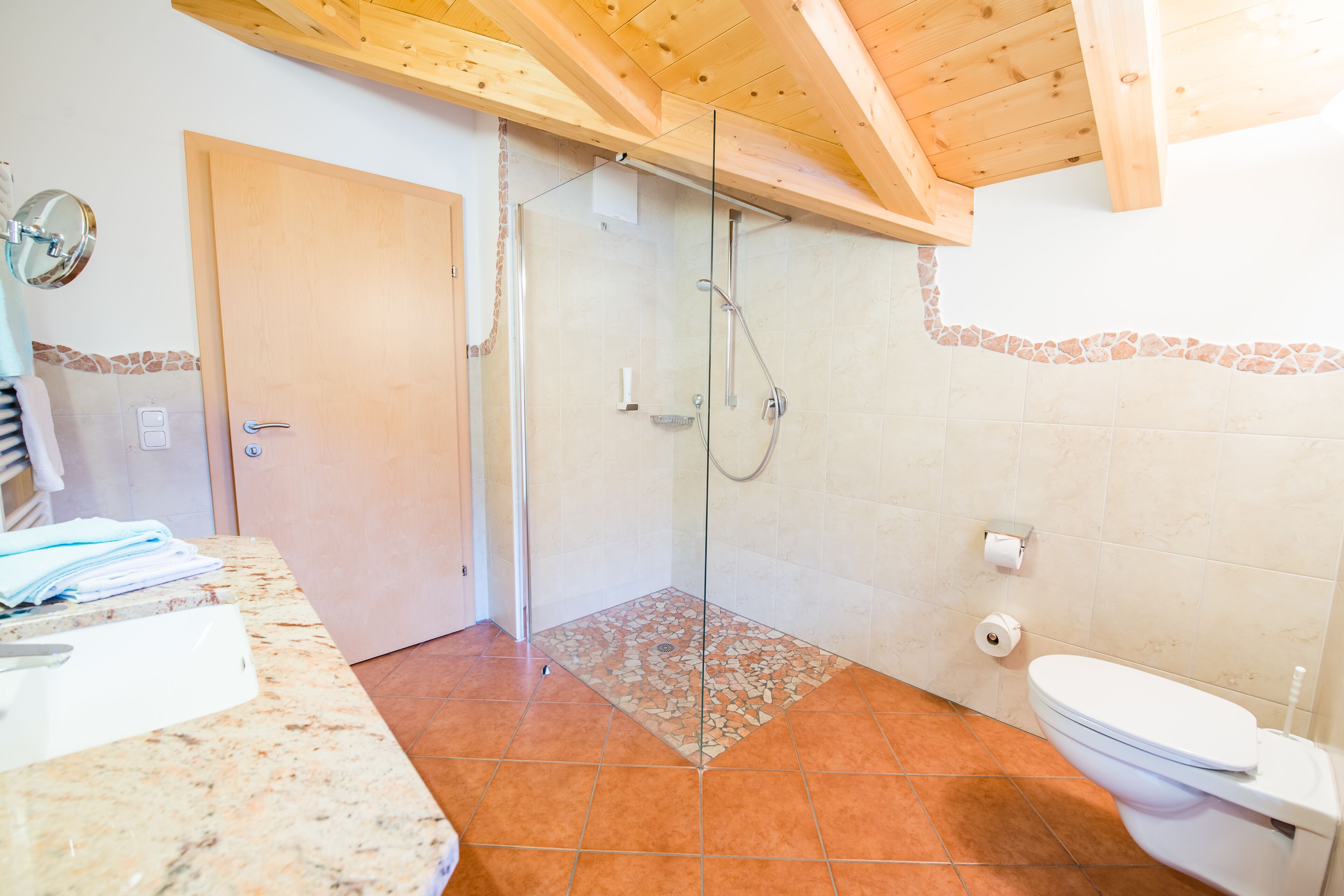 Casa de banho com chuveiro, sanita e lavatório com bancada de mármore.