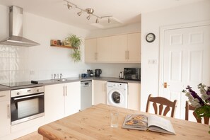 Une cuisine moderne dotée d’appareils électroménagers en acier inoxydable, d’une table à manger en bois et d’une horloge murale.