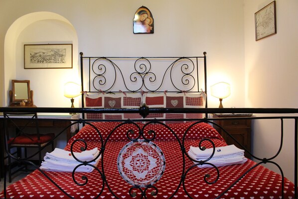 A neatly made bed with a red and white patterned bedspread, a decorative doily, and two bedside lamps. - ASSISI FAMILY HOME, the old town center with or without car (Assisi)