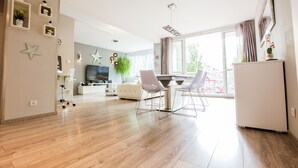 Un salon moderne comprenant un coin repas, un téléviseur et une grande fenêtre.