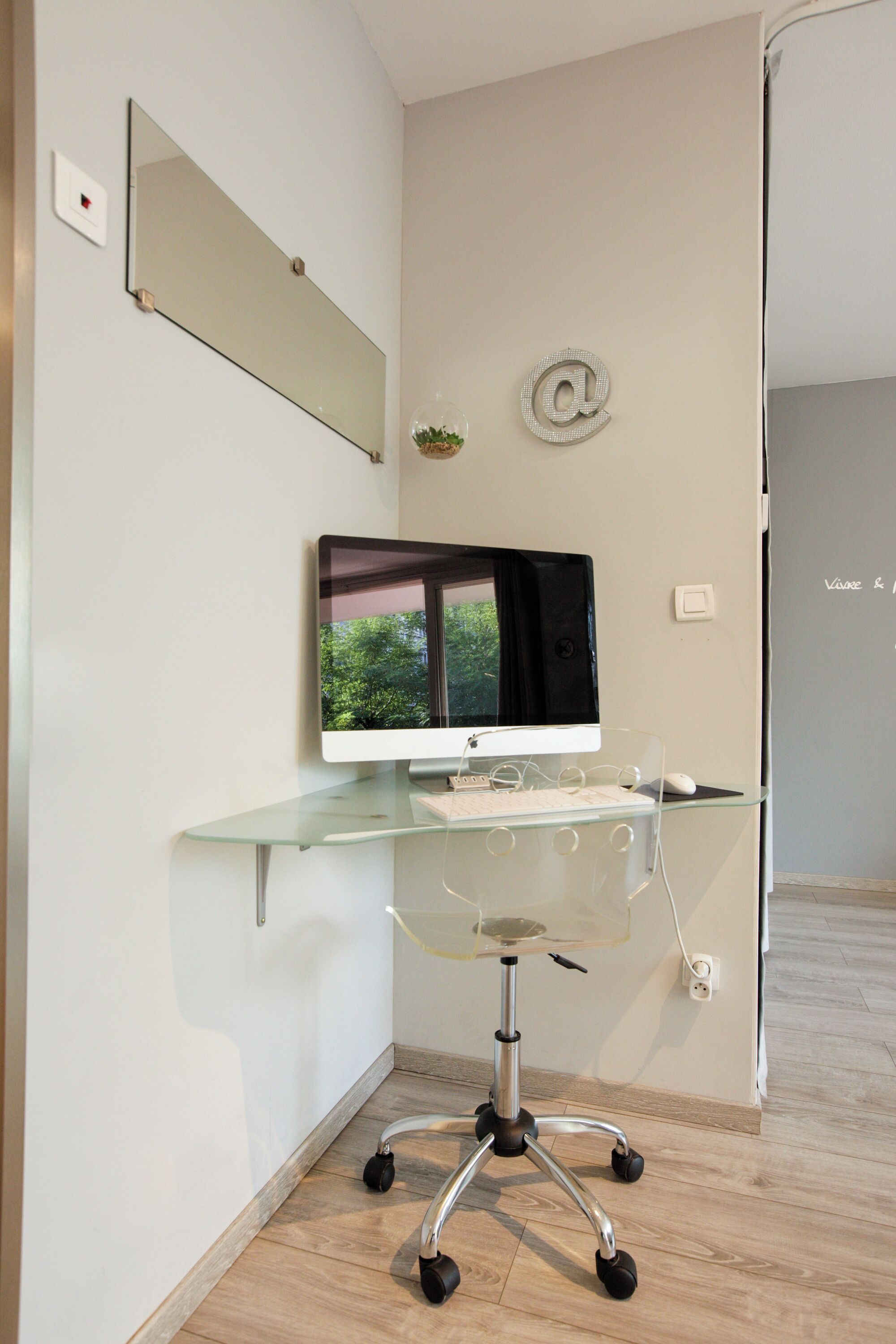 Un espace de bureau moderne avec un bureau en verre, un ordinateur de bureau et une chaise.