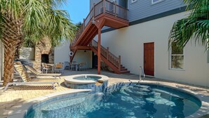 A swimming pool with a wooden deck, lounge chairs, and a stone wall. - Closest Lux Home to Beach & Seaside. See Map &Reviews! Pool, Bikes, Beach Chairs (Santa Rosa Beach)