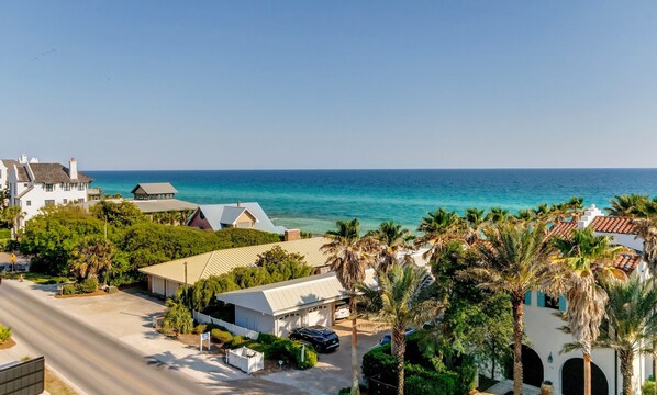 A coastal property with a view of the ocean, featuring a main house, a guest house, and a parking area.