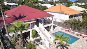 A residential area with a swimming pool, a red-roofed structure, and a white building with a balcony. - 4 Bedroom 3 Bathroom  Villa in Orient Bay, 5 min Walk to Beach and French bakery (Orient Bay)