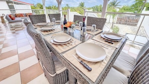 An outdoor dining area with wicker furniture, glass tables, and a tiled floor. - 4 Bedroom 3 Bathroom  Villa in Orient Bay, 5 min Walk to Beach and French bakery (Orient Bay)
