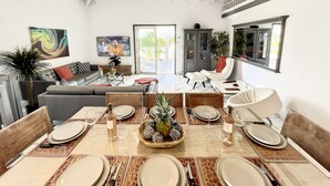 A modern living room with a dining area, white walls, ceiling fan, and large windows. - 4 Bedroom 3 Bathroom  Villa in Orient Bay, 5 min Walk to Beach and French bakery (Orient Bay)