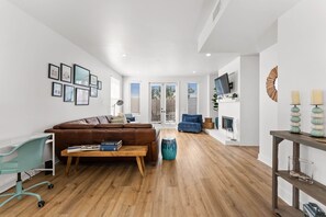 Un salon moderne avec un canapé en cuir marron, un fauteuil de bureau turquoise, une table basse en bois et un fauteuil bleu.