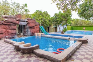 Una piscina al aire libre, sombrillas, sillones reclinables de piscina