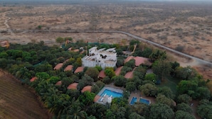 An aerial view of a residential area with multiple houses, a swimming pool, and a road. - Daksh Resort And Amusement Park (Talala)