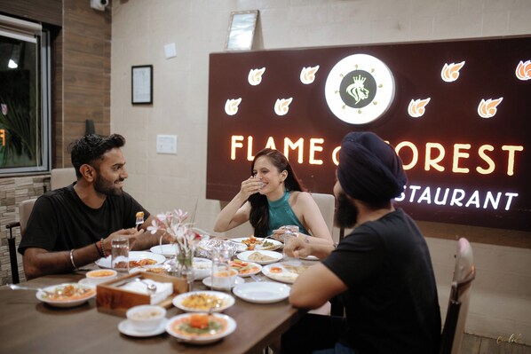 A restaurant interior with a dining table set for three people, surrounded by various dishes and a decorative vase. - Daksh Resort And Amusement Park (Talala)
