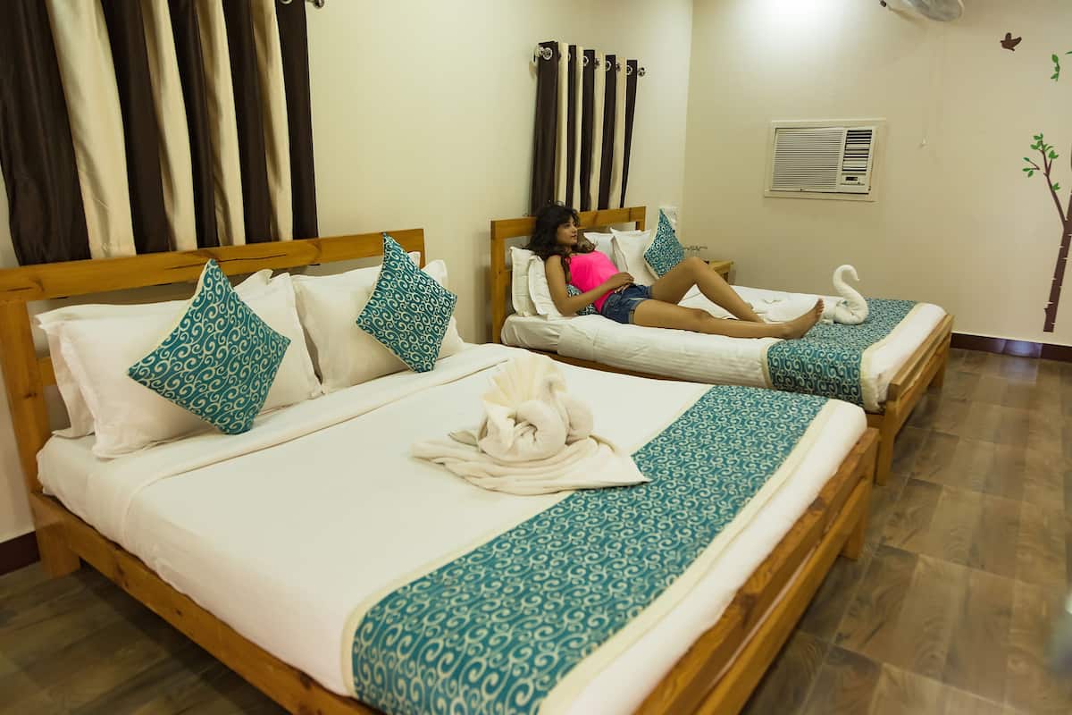Two wooden beds with patterned bedding, a wall-mounted air conditioner, and a decorative tree decal.