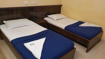 Two single beds with wooden headboards, white linens, and blue bedspreads in a hotel room.
