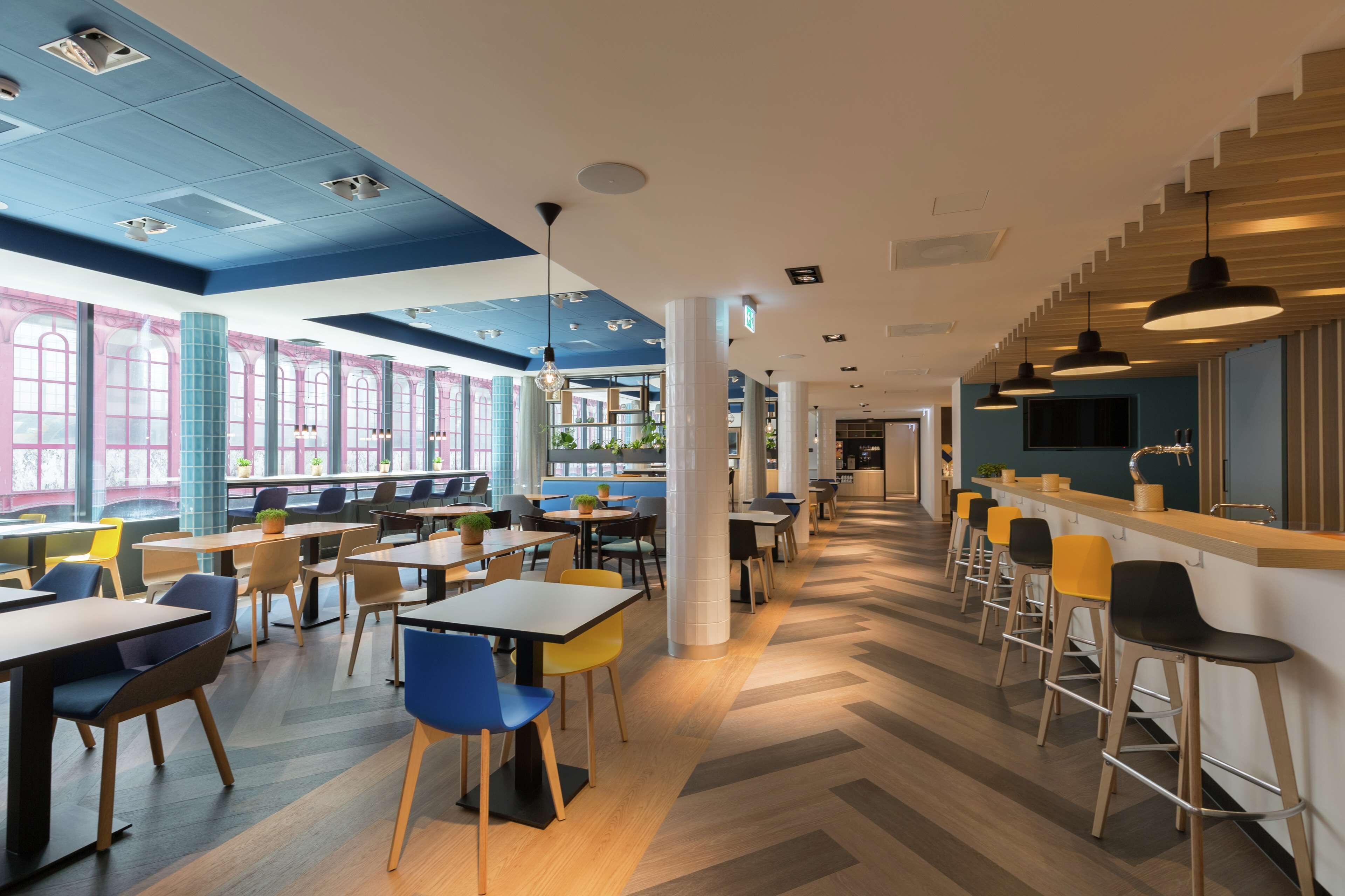 Un comedor moderno con mesas, sillas, ventanas amplias y una zona de bar.