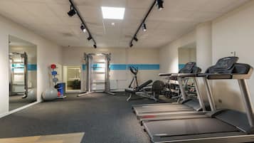 Uma academia com esteiras, aparelhos de musculação e bolas de exercício.