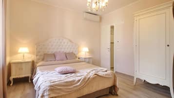 Una camera da letto con una testiera trapuntata, due lampade da comodino, un grande armadio e un lampadario.