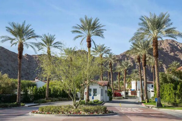 A resort area with palm trees, a small building, and mountains in the background. - Luxury Vacation- Mountain Views- 12 pools-5 star-2bed/2bath sleeps 6-063746  (La Quinta)