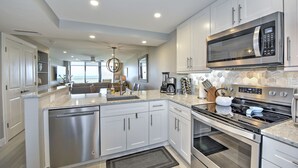 A modern kitchen with stainless steel appliances, white cabinetry, and a large island with a sink.