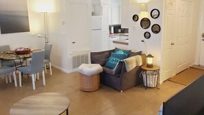 A spacious living area with a dining table, chairs, a sofa, and a television.