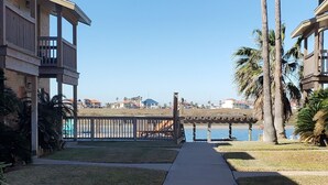A pathway leading to a waterfront with a bridge, palm trees, and residential buildings.