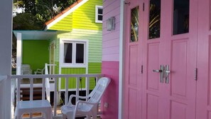A colorful house with a porch, two white plastic chairs, and a pink door. - Teeny Beach (Sichon)