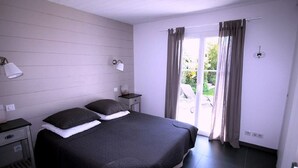 A bedroom with a large bed, two bedside tables, a nightstand, and a window with curtains.
