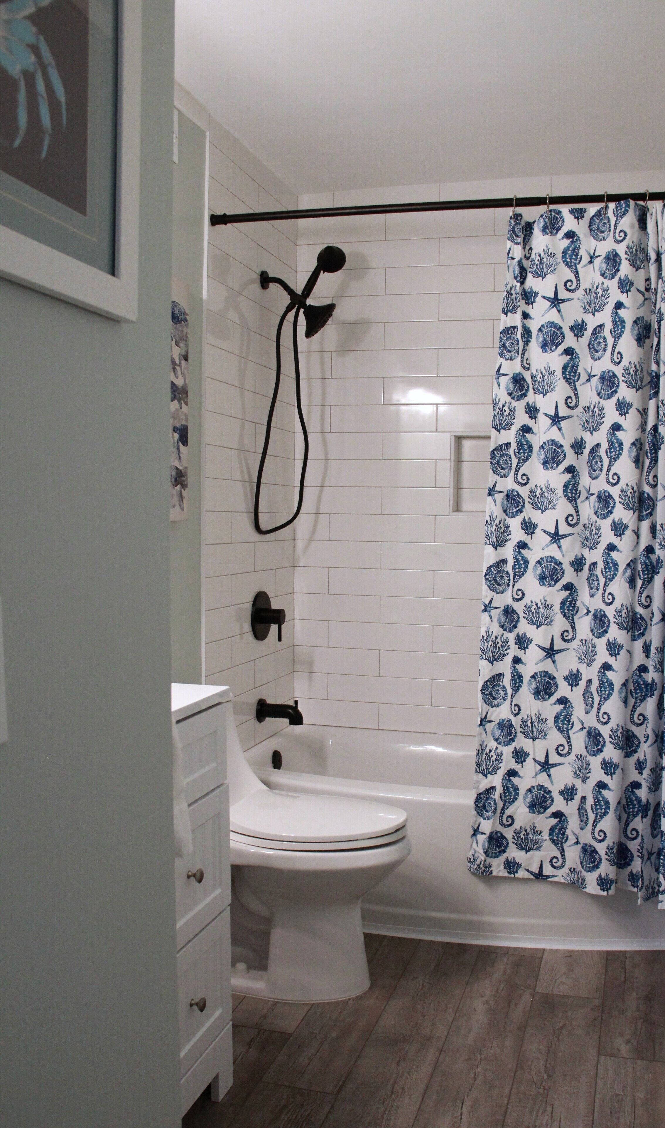 A bathroom with a white bathtub, a shower head, and a toilet.