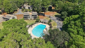 An aerial view of a residential area with a swimming pool surrounded by trees and a curved driveway. - Beautiful Renovated Pinehurst Condo I 2 Bedroom/ 2 Bath I POOL I sleeps 4 (Pinehurst)