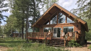 Une cabane en bois dotée d’une terrasse, entourée d’arbres.