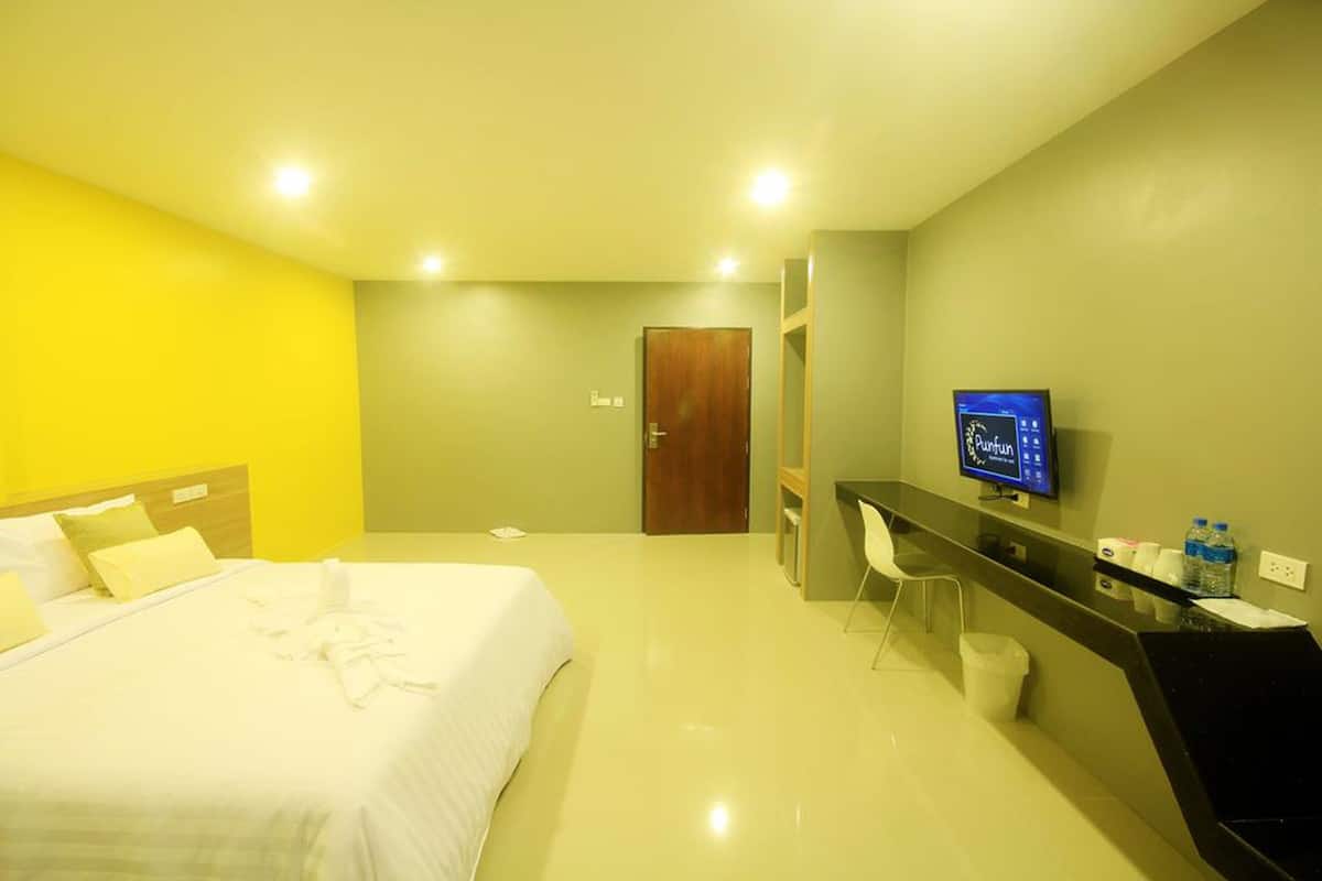 A hotel room with a bed, a desk with a chair, a television, and a door.