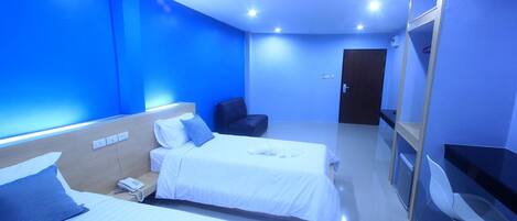 A hotel room with two beds, a desk, a chair, and a door.