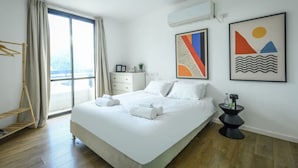 A modern hotel room with a large bed, a side table, a wardrobe, and a window with curtains. - Sea N'Rent - 185 Hayarkon Tel Aviv (Tel Aviv)