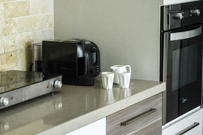 Een keuken met een koffiezetapparaat, een broodrooster en een moderne oven.