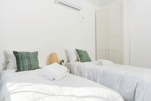 Een hotelkamer met twee bedden, witte beddengoed en een grote kast.