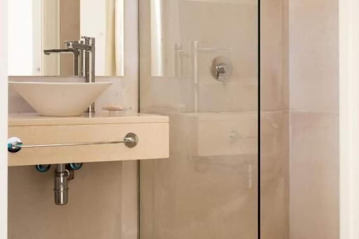Une salle de bain moderne avec une douche à parois de verre, un meuble-lavabo beige et un miroir au-dessus du meuble.