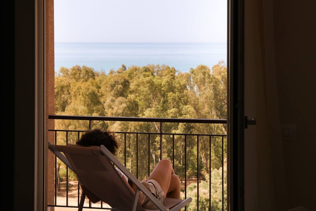 Un balcón con vista a un bosque y al mar.