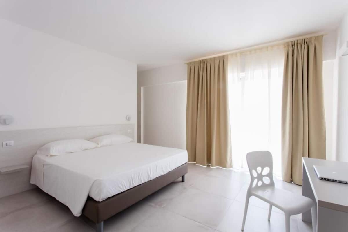 Une chambre d’hôtel moderne, équipée d’un lit, d’un bureau et d’une chaise.