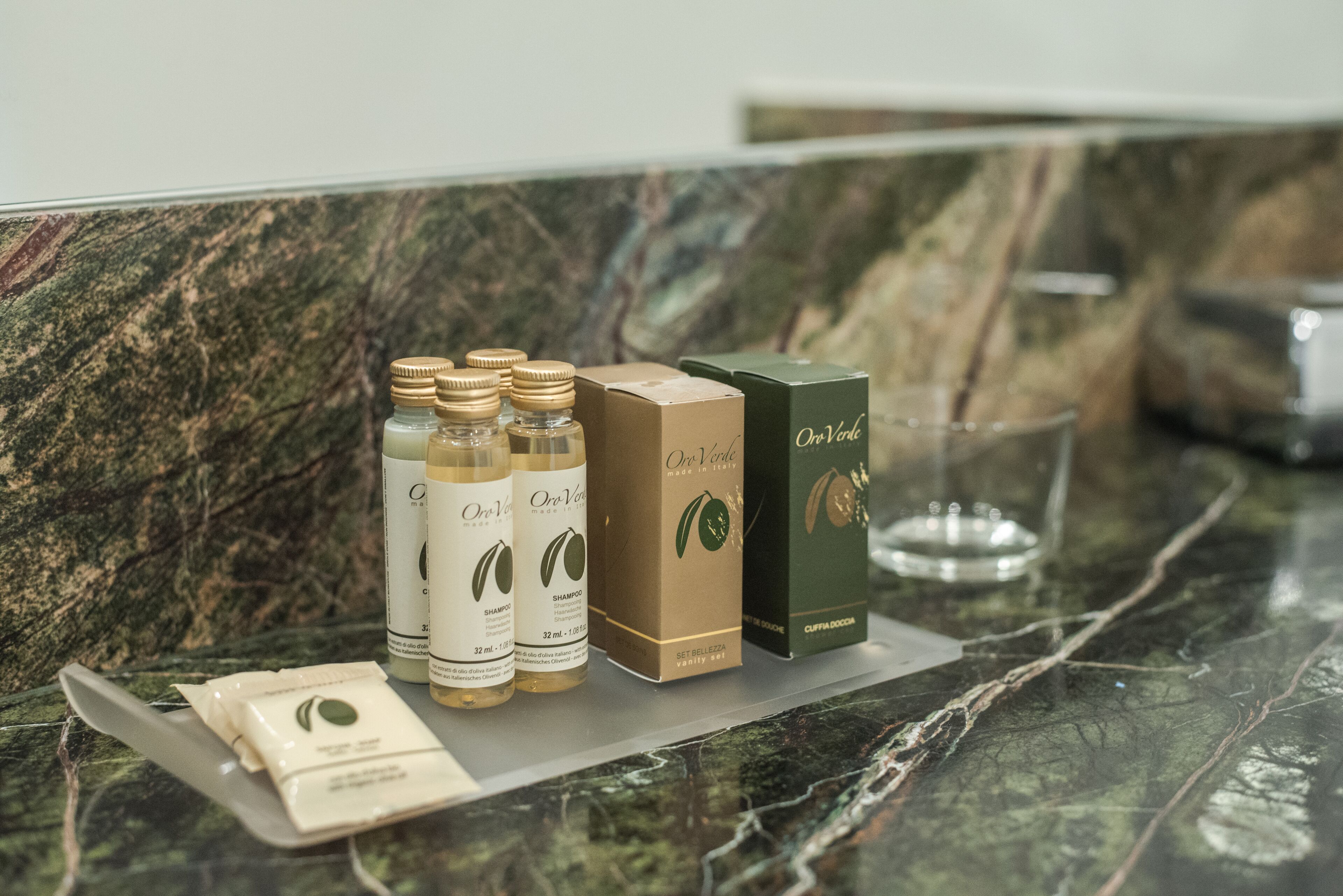 A marble countertop with a set of three bottles, two boxes, and a glass.