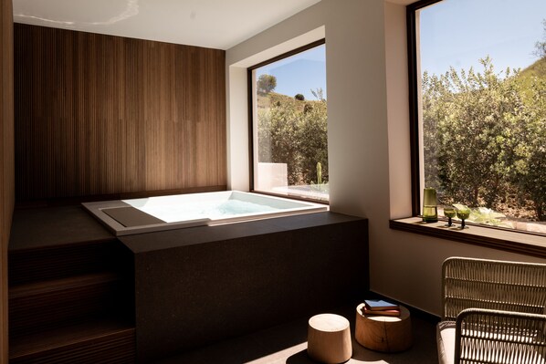 Une salle de bain moderne avec une grande baignoire, des éléments décoratifs en bois et une vue sur la verdure environnante.