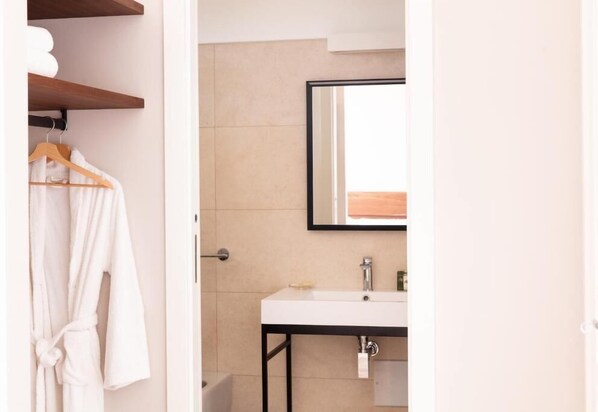 A bathroom with a white sink, a mirror, and a wooden towel rack. - Luna Minoica Suites & Apartments (Montallegro)