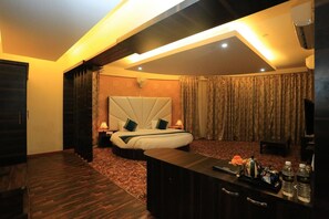 Una habitación de hotel con una cama grande, un escritorio con silla, televisión y minibar.