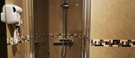 A bathroom with a glass-enclosed shower, a white sink, and a hairdryer mounted on the wall.