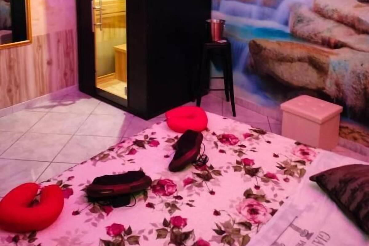 A room with a bed, a red pillow, a black cabinet, and a mural of a waterfall.