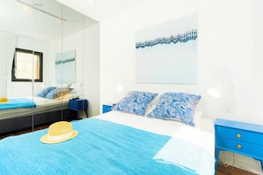 A bedroom with a bed, a large mirror, a wall-mounted artwork, and a blue nightstand. - MAMAD - Jaffa Charm Seaview Stay by Sea N' Rent (Tel Aviv)