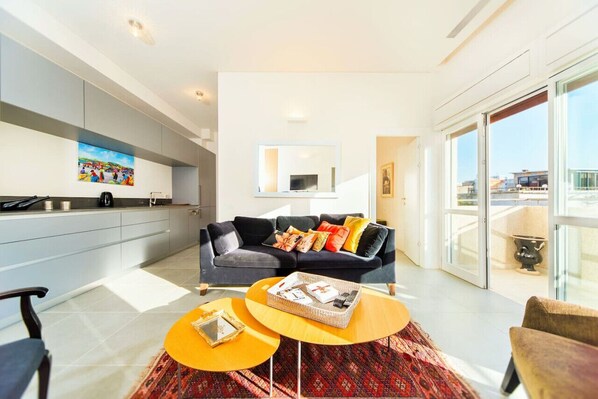 A modern living space with a sofa, coffee table, and a kitchen area. - MAMAD - Sea N'Rent - 204 Ben Yehuda Tel Aviv (Tel Aviv)