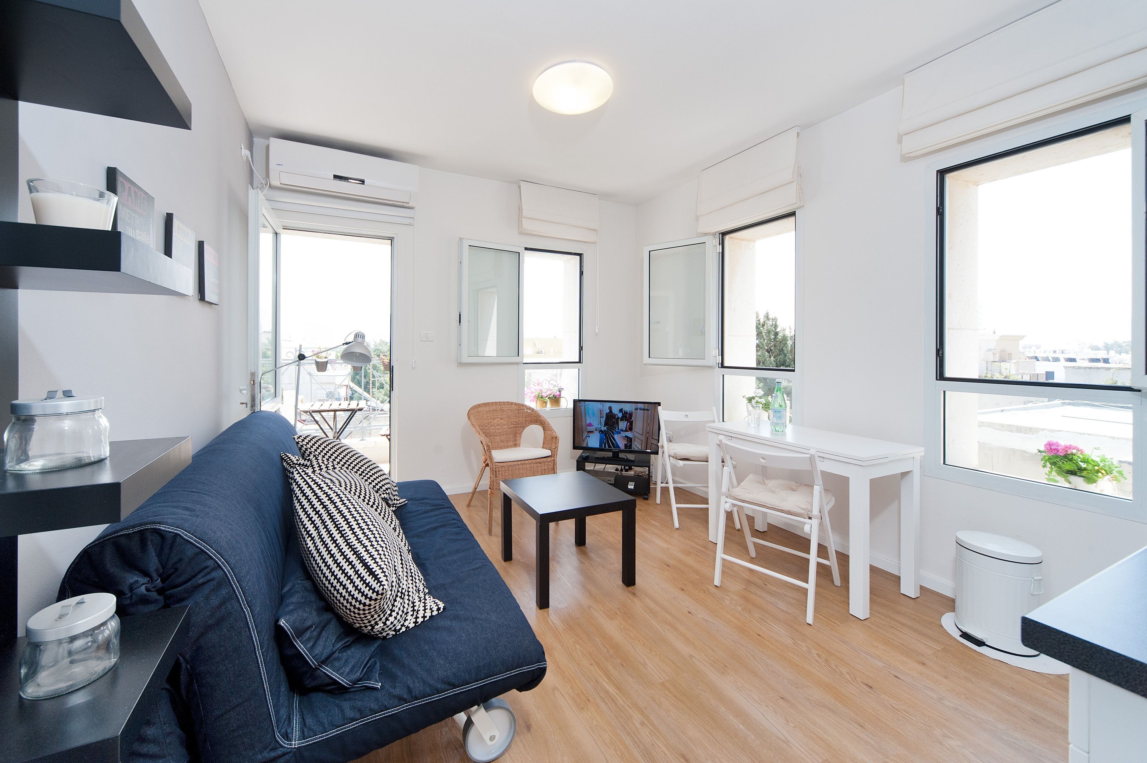 A modern living room with a sofa, a dining table, and a TV.