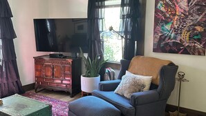 Een woonkamer met een bank, een televisie, een plant en een schilderij.