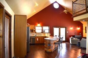 A spacious kitchen with wooden cabinets, a central island, and a dining area with chairs. - 11 acre Hill Country Retreat with a 2000 sq ft deck.  (Dripping Springs)
